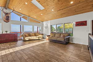 Living room featuring high vaulted ceiling, a skylight, wooden ceiling, plenty of natural light, and light wood-type flooring