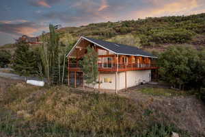 Back of property at dusk with a patio and a wooden deck