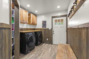 Laundry area with light wood-style floors, cabinet space, wainscoting, recessed lighting, and washer and dryer