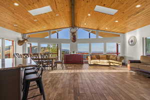 Living room with a skylight, light wood-style floors, high vaulted ceiling, a wooden ceiling with exposed beams, and recessed lighting