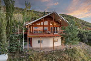 Rear view of property featuring a wooden deck and a wooded view