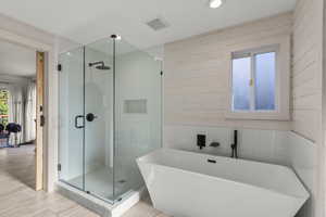Full bath with a stall shower, a soaking tub, wood walls, tile walls, and recessed lighting