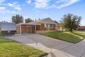 View of front facade featuring concrete driveway, brick siding, a patio, and an attached carport