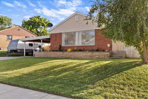 View of front of property featuring a front lawn, a carport, and brick siding