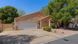 Mediterranean / spanish-style house with a tile roof, driveway, a gate, stucco siding, and a garage