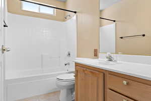 Bathroom with light tile patterned floors, vanity, and shower / tub combination