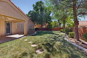 Fenced backyard with ceiling fan and a patio area