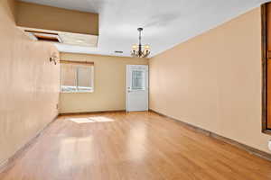 Unfurnished room with light wood finished floors and a chandelier