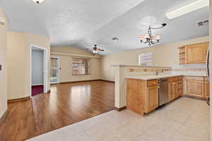 Kitchen with light countertops, a peninsula, healthy amount of natural light, a ceiling fan, and lofted ceiling