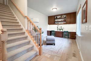 Bar area featuring built in study area, light countertops, light wood-type flooring, stairway, and a textured ceiling