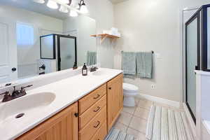 Bathroom featuring double vanity, a stall shower, and light tile patterned flooring