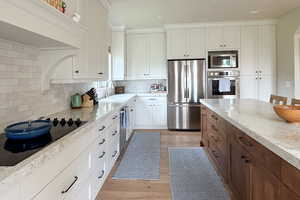 Kitchen featuring stainless steel appliances, backsplash, light wood finished floors, white cabinetry, and recessed lighting