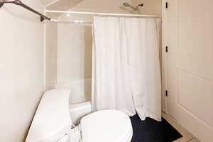 Full bath featuring shower / bath combination with curtain and tile patterned flooring