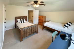Carpeted bedroom with vaulted ceiling and ceiling fan