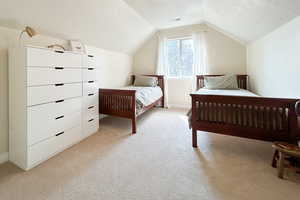 Bedroom featuring a textured ceiling, light carpet, and lofted ceiling