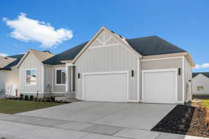 View of front of property featuring board and batten siding, roof with shingles, driveway, a garage, and a front yard