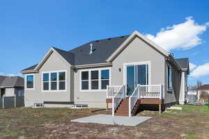 Rear view of house with stucco siding, roof with shingles, a wooden deck, and a patio