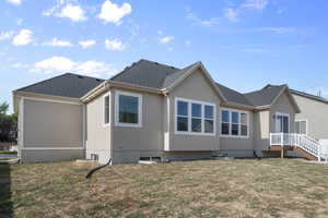 Back of property with a yard and roof with shingles