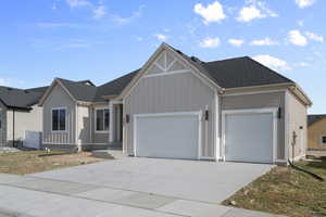 View of front of house featuring an attached garage, driveway, and a shingled roof