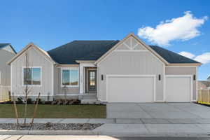 View of front of house with a shingled roof, a front lawn, driveway, a garage, and board and batten siding