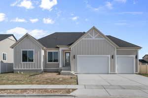 View of front facade featuring a shingled roof, an attached garage, and concrete driveway