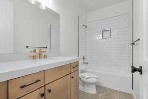 Bathroom with washtub / shower combination, vanity, and light tile patterned flooring