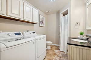 Washroom with a textured ceiling, washer and clothes dryer, and light tile patterned floors