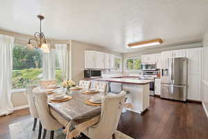 Dining space featuring a textured ceiling, dark wood-style flooring, and a chandelier