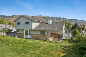 Back of house featuring brick siding, a mountain view, a gate, and a chimney