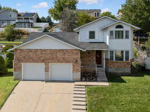 Traditional-style house featuring brick siding, concrete driveway, an attached garage, covered porch, and a residential view
