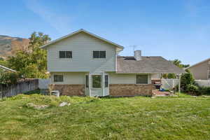 Back of property featuring brick siding, a fenced backyard, a gate, and a chimney