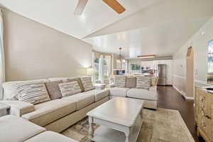 Living room featuring hardwood / wood-style flooring, vaulted ceiling, ceiling fan, and arched walkways