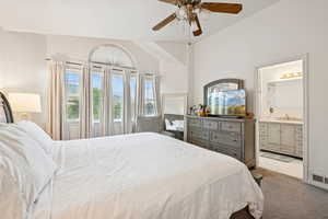 Bedroom with carpet flooring, vaulted ceiling, a ceiling fan, and connected bathroom