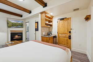 Bedroom featuring beam ceiling, a glass covered fireplace, recessed lighting, and dark wood finished floors