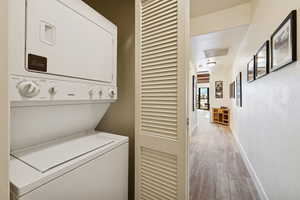 Washroom featuring stacked washer and clothes dryer and light carpet