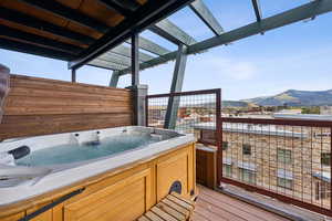 Wooden deck with a hot tub and a mountain view
