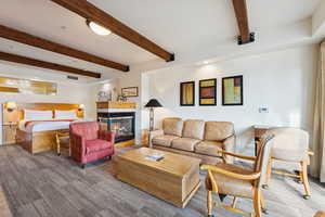 Living area featuring beam ceiling and a tiled fireplace