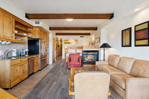 Living area with light tile patterned flooring, beam ceiling, a multi sided fireplace, and recessed lighting
