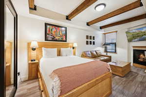 Bedroom featuring a glass covered fireplace and beamed ceiling