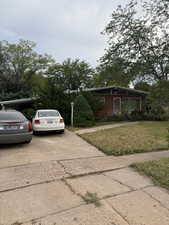 View of side of property featuring concrete driveway, a yard, and brick siding