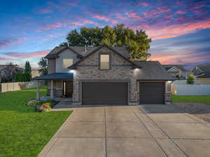 View of front facade featuring concrete driveway, covered porch, roof with shingles, and an attached garage