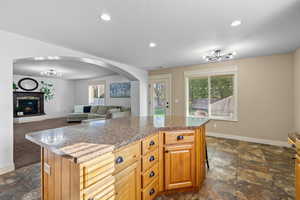 Kitchen with a center island, open floor plan, recessed lighting, arched walkways, and a glass covered fireplace