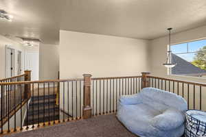 Living area with a textured ceiling, an upstairs landing, and carpet