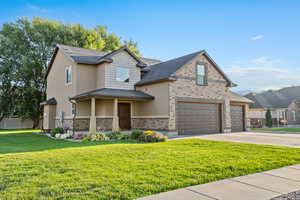 View of front of house featuring driveway, brick siding, stucco siding, and a garage