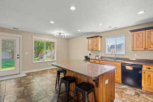 Kitchen with a kitchen breakfast bar, black dishwasher, a center island, recessed lighting, and a textured ceiling