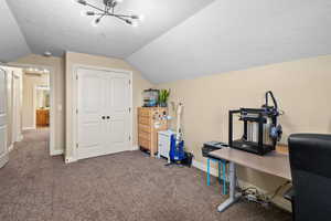 Carpeted office space with vaulted ceiling, a textured ceiling, and a chandelier