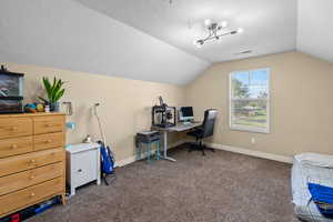 Carpeted home office with a textured ceiling, vaulted ceiling, and a chandelier