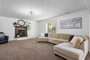 Carpeted living area with a textured ceiling and a high end fireplace