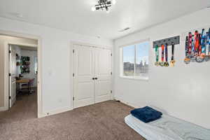 Carpeted bedroom with a closet and a desk