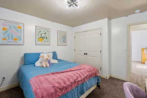 Carpeted bedroom with a closet and a textured ceiling